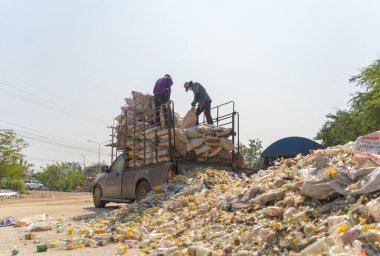 Çevre kirliliği kavramının kentsel alanındaki büyük çöp yığını, plastik torbalar ve çöp bidonları üzerinde çalışan işçiler.