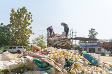 Çevre kirliliği kavramının kentsel alanındaki büyük çöp yığını, plastik torbalar ve çöp bidonları üzerinde çalışan işçiler.