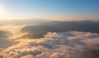 Orman ağaçlarının ve deniz sisi, sis ve bulutlu yeşil dağ tepelerinin havadan görünüşü. Doğa manzarası arka planı, Tayland.