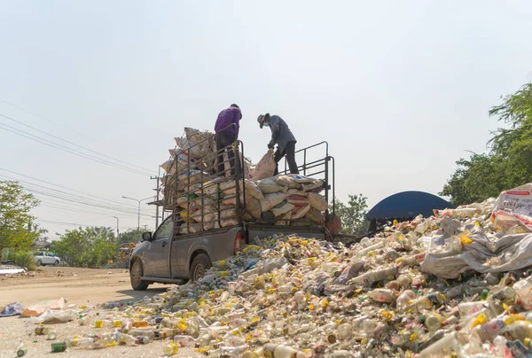 Çevre kirliliği kavramının kentsel alanındaki büyük çöp yığını, plastik torbalar ve çöp bidonları üzerinde çalışan işçiler.