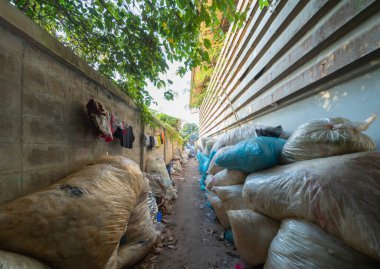 Çevre kirliliği kavramının kentsel alanındaki farklı türde çöp yığını, plastik torbalar, şişeler ve çöp bidonları içeren fabrika endüstrisi.
