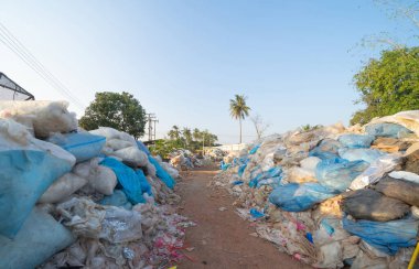 Çevre kirliliği kavramının kentsel alanındaki farklı türde çöp yığını, plastik torbalar, şişeler ve çöp bidonları içeren fabrika endüstrisi.