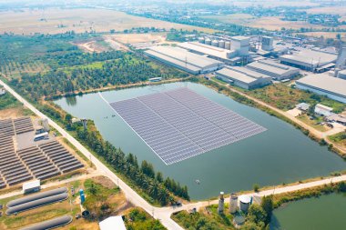 Göldeki ya da nehirdeki çiftliğin çatısındaki güneş panelleri ya da güneş hücrelerinin hava görüntüsü. Yeşil alanı olan bir enerji santrali, yenilenebilir temiz enerji kaynağı. Sanayide elektrik enerjisi için eko teknoloji.