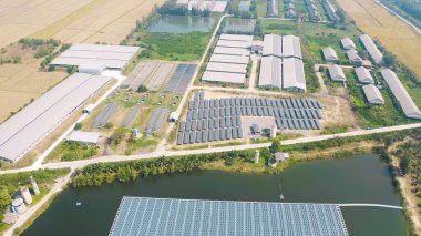 Çiftlikteki çatıdaki güneş panelleri veya güneş pillerinin havadan görüntüsü. Yeşil alanı olan bir enerji santrali, yenilenebilir temiz enerji kaynağı. Sanayide elektrik enerjisi için eko teknoloji.