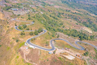 Tayland 'ın Nan kentinin kırsal kesiminde yeşil orman ağaçlarının bulunduğu dağ tepesindeki kavisli, zikzaklı yolda veya caddede giden arabaların hava manzarası. Ulaşım.