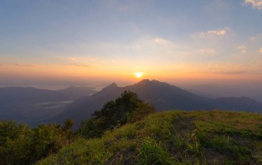 Orman ağaçlarının ve sisli, bulutlu yeşil dağ tepelerinin havadan görünüşü. Doğa manzarası arka planı, Tayland.