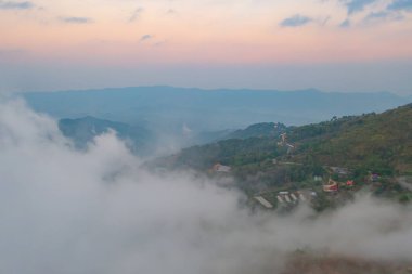 Orman ağaçlarının ve sisli, bulutlu yeşil dağ tepelerinin havadan görünüşü. Doğa manzarası arka planı, Tayland.