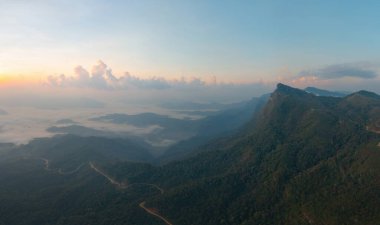 Orman ağaçlarının ve sisli, bulutlu yeşil dağ tepelerinin havadan görünüşü. Doğa manzarası arka planı, Tayland.