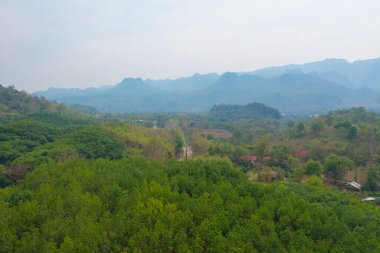 Orman ağaçlarının ve sisli, bulutlu yeşil dağ tepelerinin havadan görünüşü. Doğa manzarası arka planı, Tayland.
