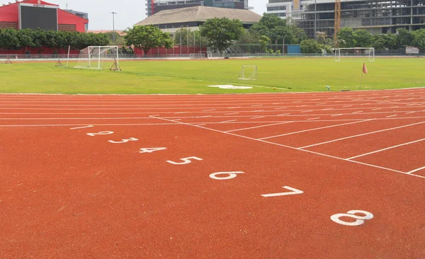 Rubber floor, red running track on a sports stadium with grandstand. Sport and recreation background.