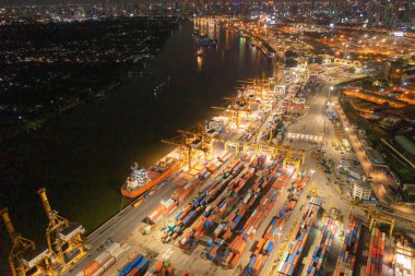 Şehir merkezindeki iş ve lojistik uluslararası malların ihracat ve ithalatındaki konteyner kargo gemisinin hava görüntüsü. Geceleyin Tayland 'ın Bangkok limanındaki vinçle limana gidecek..