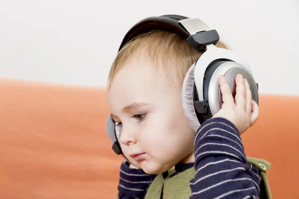 Niño pequeño en el sofá con auriculares —  Fotos de Stock