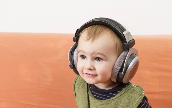 Маленька дитина на дивані з навушниками — стокове фото