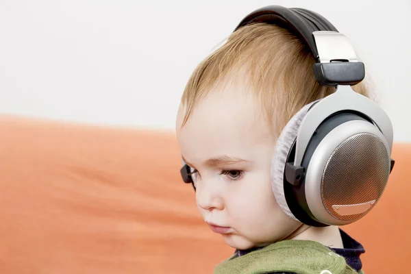 Μικρό παιδί στον καναπέ με ακουστικών — Φωτογραφία Αρχείου