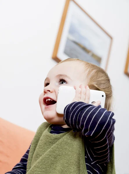 Маленька дитина на дивані з мобільним телефоном — стокове фото