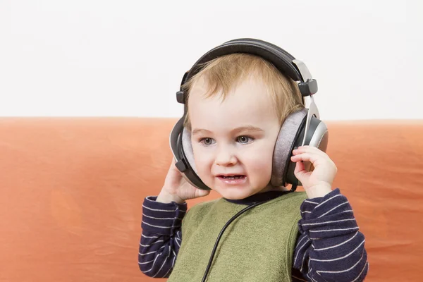 Young child on couch with headphone — Stock Photo, Image