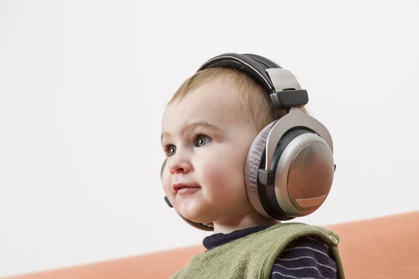 Niño pequeño en el sofá con auriculares —  Fotos de Stock