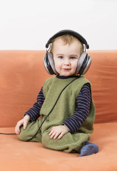 Niño pequeño en el sofá con auriculares —  Fotos de Stock