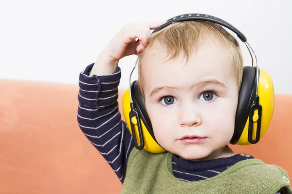 Malé dítě na gauči s Chrániče uší — Stock fotografie