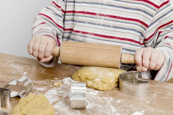 Child rolling dough on wooden desk — Stock Photo, Image