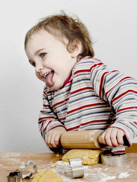 Glückliches kleines Kind mit Nudelholz im grauen Hintergrund — Stockfoto
