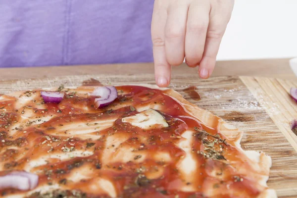 Hand making fresh pizza on wooden board — Stock Photo, Image