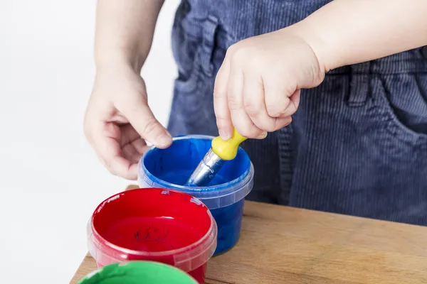 Child holding brush in paint tub — Stock Photo, Image