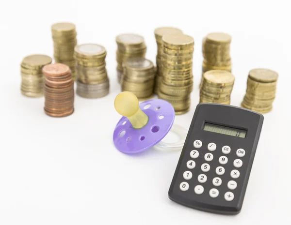 Pacifier with hard money and pocket calculator — Stock Photo, Image