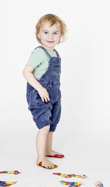Kind met geschilderde voeten houden broek — Stockfoto