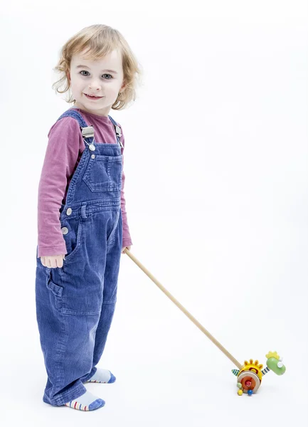 Peuter met speelgoed staande in lichte achtergrond — Stockfoto