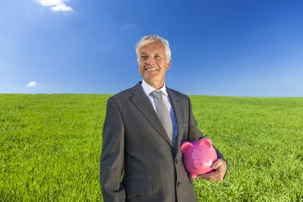 Geschäftsmann hält Sparschwein im Feld — Stockfoto