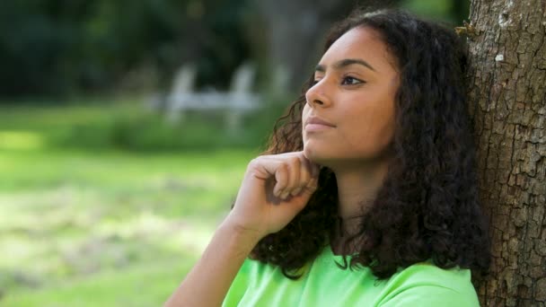 美丽的混血儿非洲裔美国女孩出生时 年轻女子坐在外面悲伤或沮丧的靠着一棵树坐着 — 图库视频影像