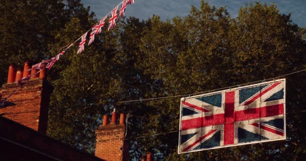 イギリス イギリス イギリスの通りの家から飛んでくるユニオンジャックの旗 — ストック動画