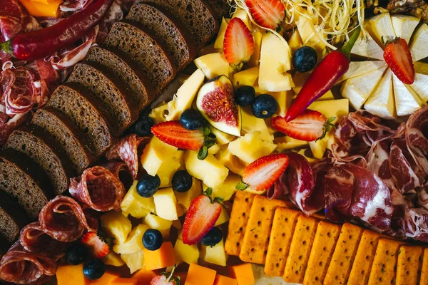 Mesa rica con diferentes tipos de bocadillos de embutidos, queso de pan y frutas Imagen de stock