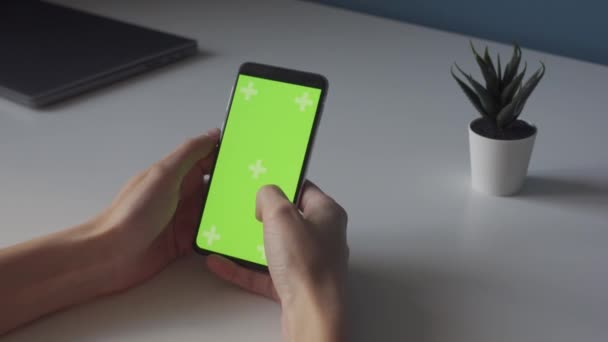 Tecla de croma de pantalla verde en smartphone en mesa blanca con planta pequeña — Vídeo de stock