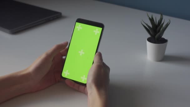 Green screen chroma key on smartphone on white table with small plant — Stockvideo