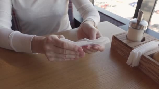 Femme à une table dans un restaurant se frotte les mains avec une serviette antibactérienne — Video