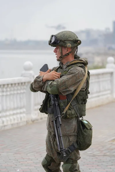 Hombre con uniforme militar en terraplén con brazos alrededor de una ametralladora Imagen de stock
