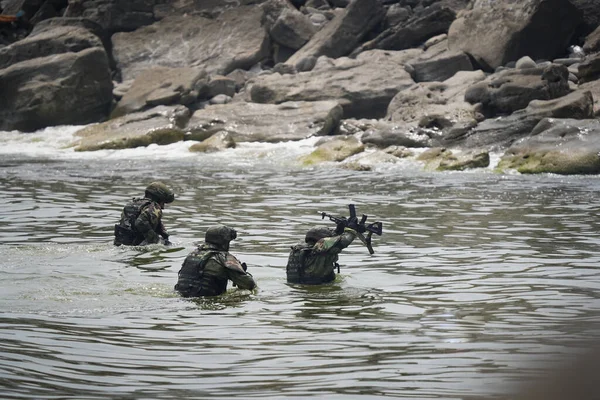 Trois soldats en uniforme militaire sortent de l'eau vers le rivage Images De Stock Libres De Droits
