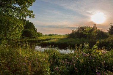 Küçük bir nehrin üzerinde gün batımı manzarası