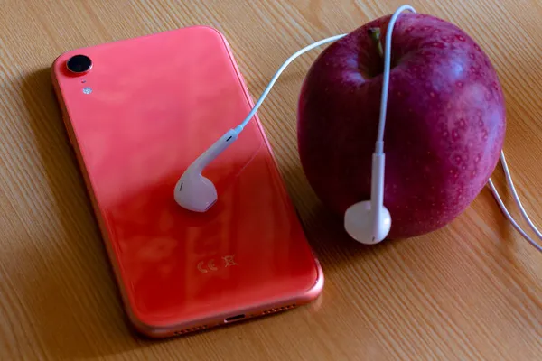 Cep telefonu, elma ve kulaklık masada.