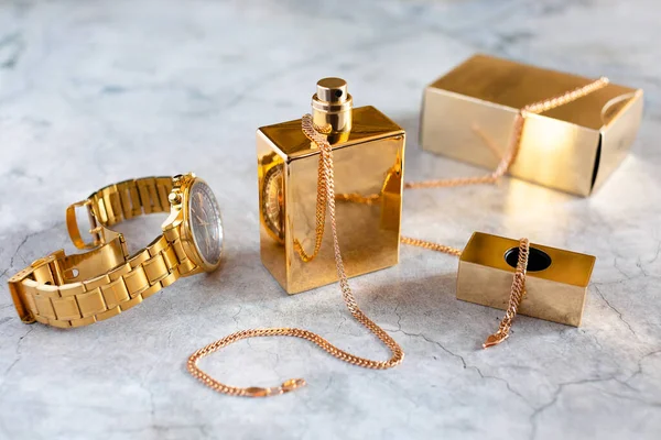 Altın bir şişe ve saat içinde erkek parfümü.