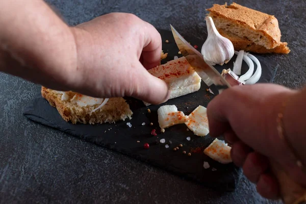 Siyah bir kesme tahtasının üzerinde domuz yağı dilimlemek