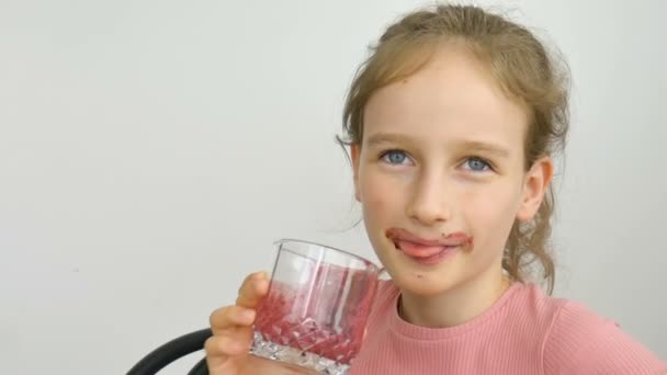 甘い女の子はラズベリースムージーと笑顔を飲みます。ベジタリアンドリンク。さわやかなおいしいラズベリージュース、健康的な食事を楽しむ子供のクローズアップ肖像画 — ストック動画
