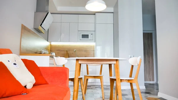 Современный интерьер кухни с деревянными и белыми элементами, ярко-оранжевый диван, бытовая жизнь, интерьер витрины. — стоковое фото