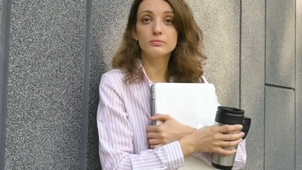 Žena portrét mladé ženy se stříbrným notebookem a šálkem kávy čeká na setkání u tmavě šedé stěny v dopoledních hodinách, vzdálená práce, káva ebreak, chytrý studentský koncept — Stock video
