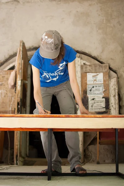 13.08.2021 - Ucraina, Goshcha, operaia stanno facendo dei segni sulla tavola di legno per i buchi futuri usando la matita per assemblare il banco durante l'evento volontario. — Foto Stock