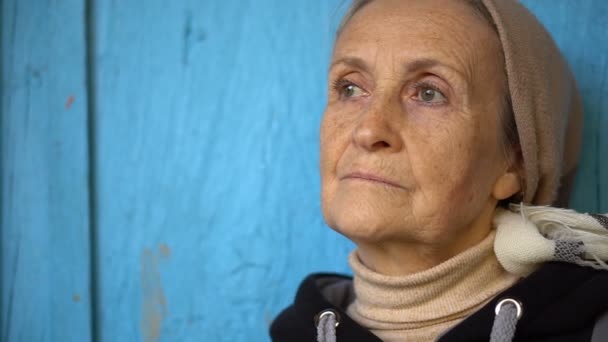 Ritratto femminile di bella donna anziana in fazzoletto o scialle in piedi vicino a droor di legno blu all'aperto — Video Stock