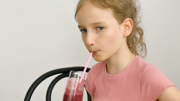 Γλυκό κοριτσάκι πίνει σμούθι βατόμουρο και χαμογελά. Χορτοφαγικό ποτό. Κοντινό πλάνο πορτρέτο ενός παιδιού που απολαμβάνει ένα δροσιστικό νόστιμο χυμό βατόμουρο, υγιεινή διατροφή — Αρχείο Βίντεο