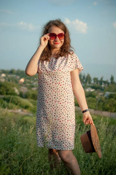 Молодая девушка в платье отлично проводит время во время летних каникул на фоне неба на природе, путешествуя по миру — стоковое фото